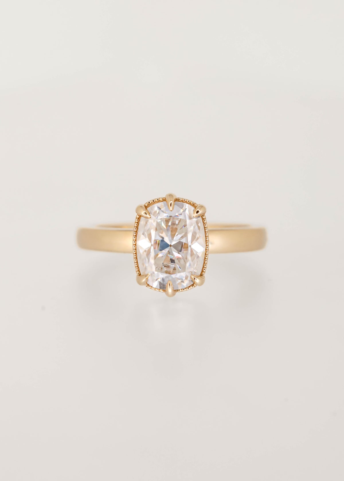 Elongated cushion moissanite solitaire engagement ring in 14K yellow gold with a six prong basket and milgrain detailing