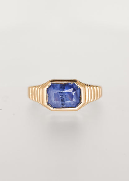Masculine leaning east west emerald cut blue sapphire engagement ring in 14K yellow gold with a sculptural ribbed signet bezel