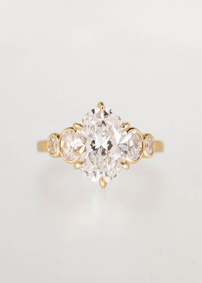 Five stone oval cut lab grown diamond engagement ring in 14K yellow gold with a six prong center and graduated bezel side stones