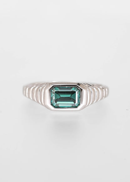 Gender neutral east west emerald cut teal moissanite engagement ring in 14K white gold with a sculptural ribbed signet bezel