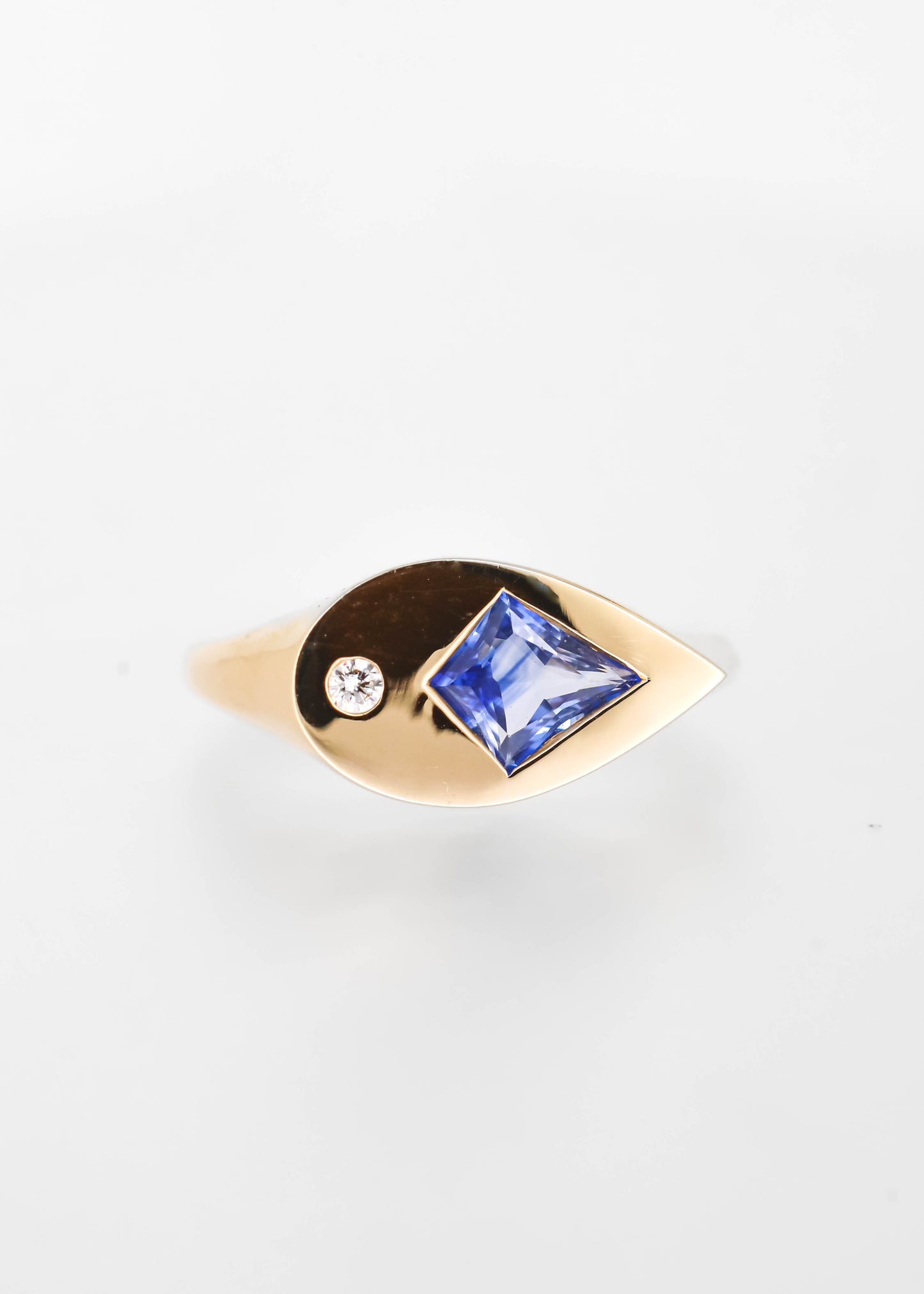 Unique gender neutral kite cut blue sapphire signet ring in 14K yellow gold with an asymmetrical bezel and small natural diamond accent