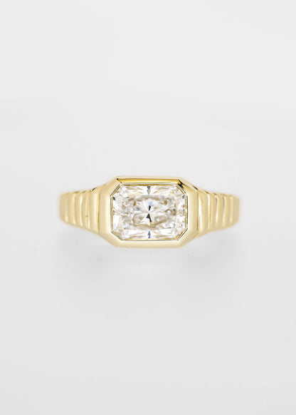 East west bezel set radiant cut lab grown diamond engagement ring in 14K yellow gold with a ribbed band