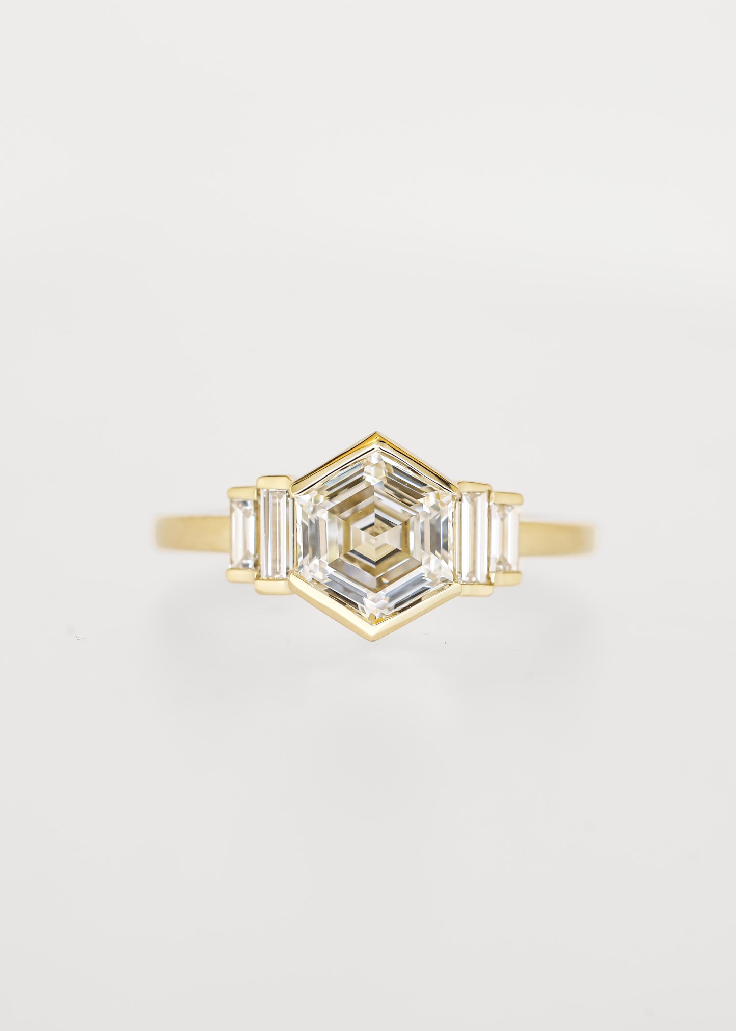 Bezel set hexagon lab grown diamond engagement ring in 14K yellow gold with graduated baguette accent stones