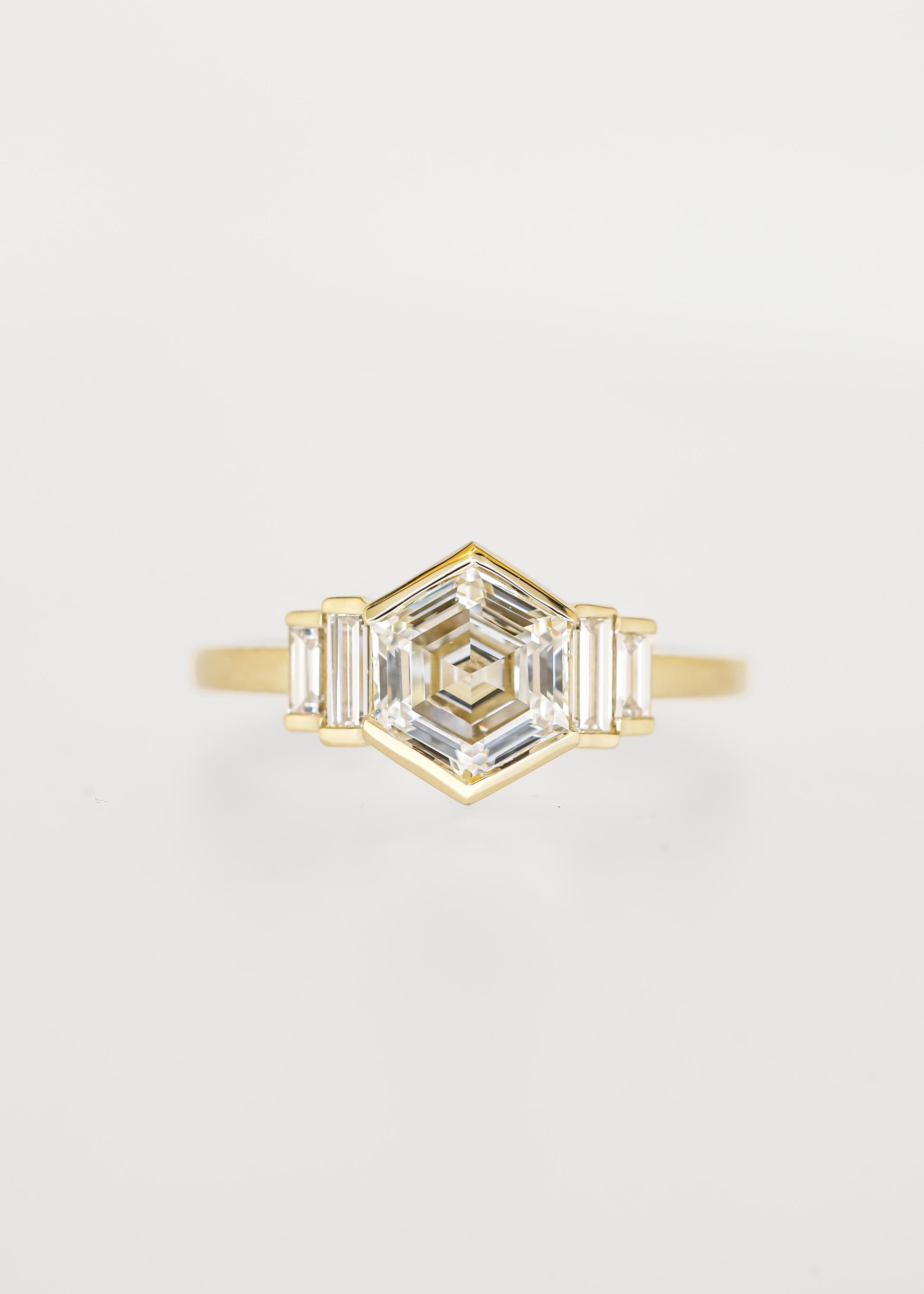 Bezel set hexagon lab grown diamond engagement ring in 14K yellow gold with graduated baguette accent stones