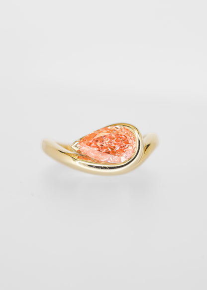 East west bezel set pear lab grown pink diamond engagement ring in 14K yellow gold with a curved sculptural band