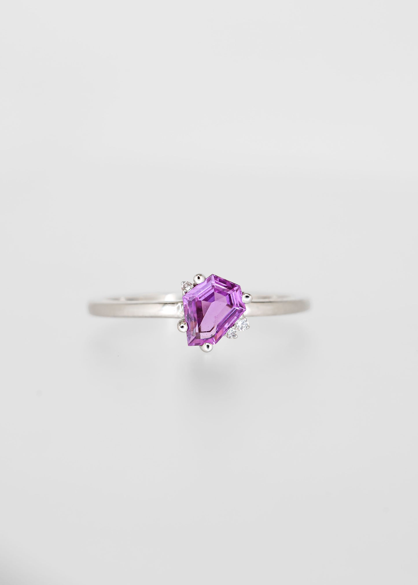 Shield cut pink sapphire engagement ring in 14K white gold with asymmetric round diamond accent stones