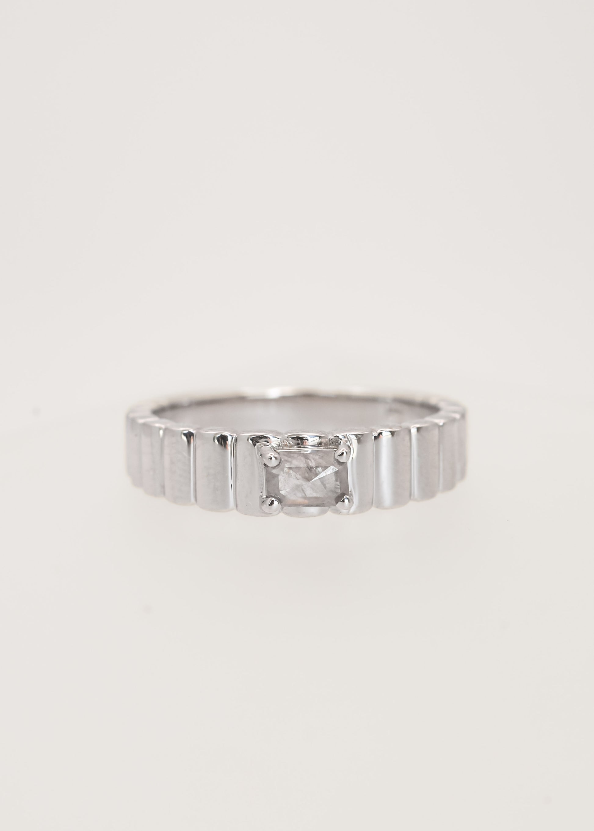 Gender neutral emerald cut salt and pepper diamond engagement ring in 14K white gold with a textured ribbed band and four prong setting