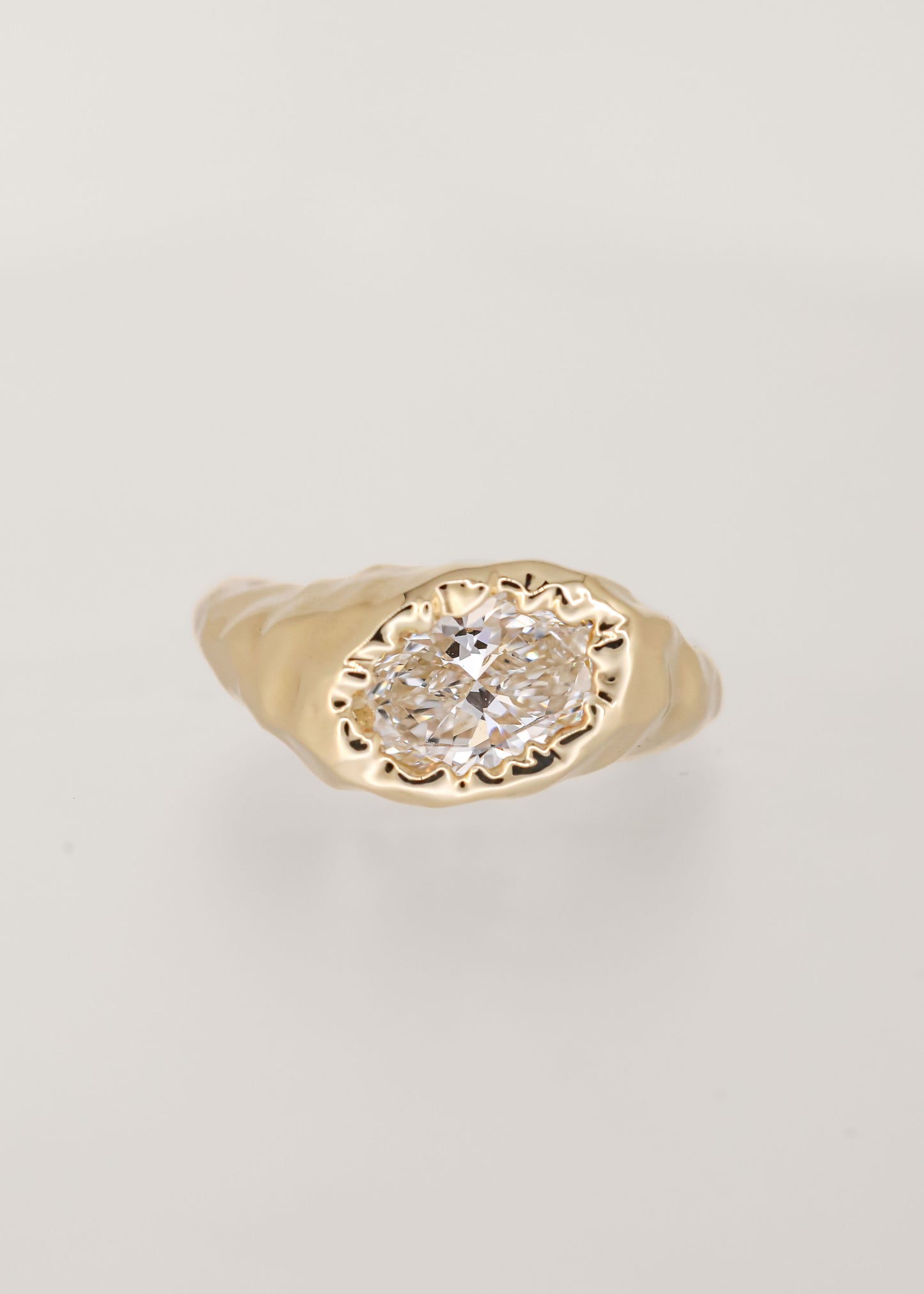 Gender neutral asymmetrical oval lab grown diamond engagement ring in melty 14K yellow gold with an organic drippy bezel setting