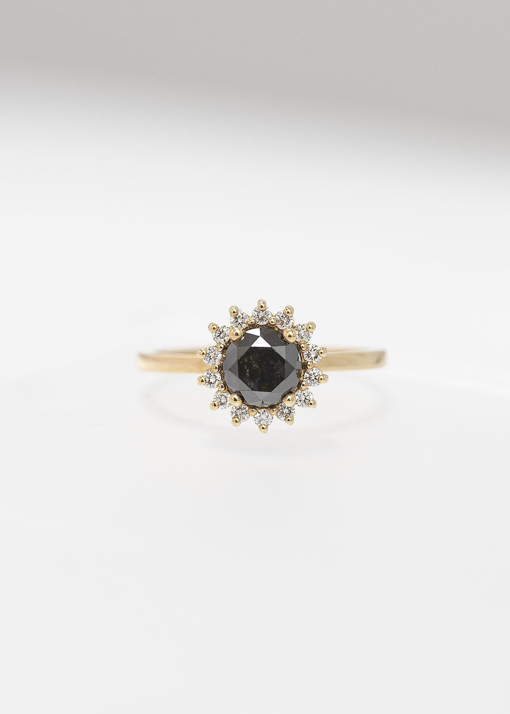 Round black diamond sunburst halo engagement ring in 14K yellow gold with a white diamond halo