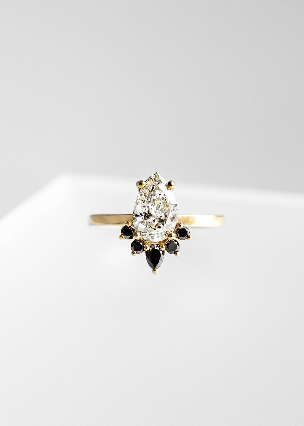 Pear shape diamond engagement ring in 14K yellow gold with a crown of black diamond accent stones