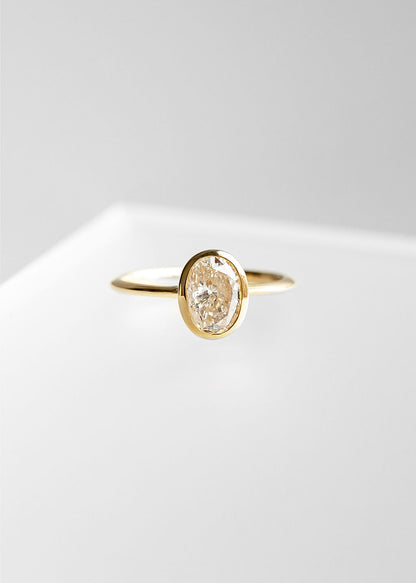 Minimal oval natural diamond bezel solitaire engagement ring in 14K yellow gold with a dainty band and low setting