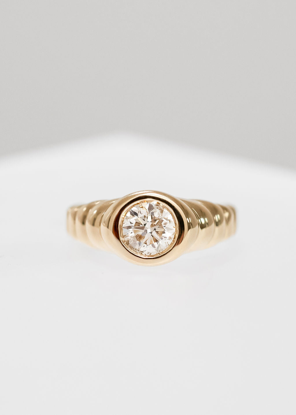 Gender neutral round natural diamond signet engagement ring in 14K yellow gold with a unique ribbed band and full bezel